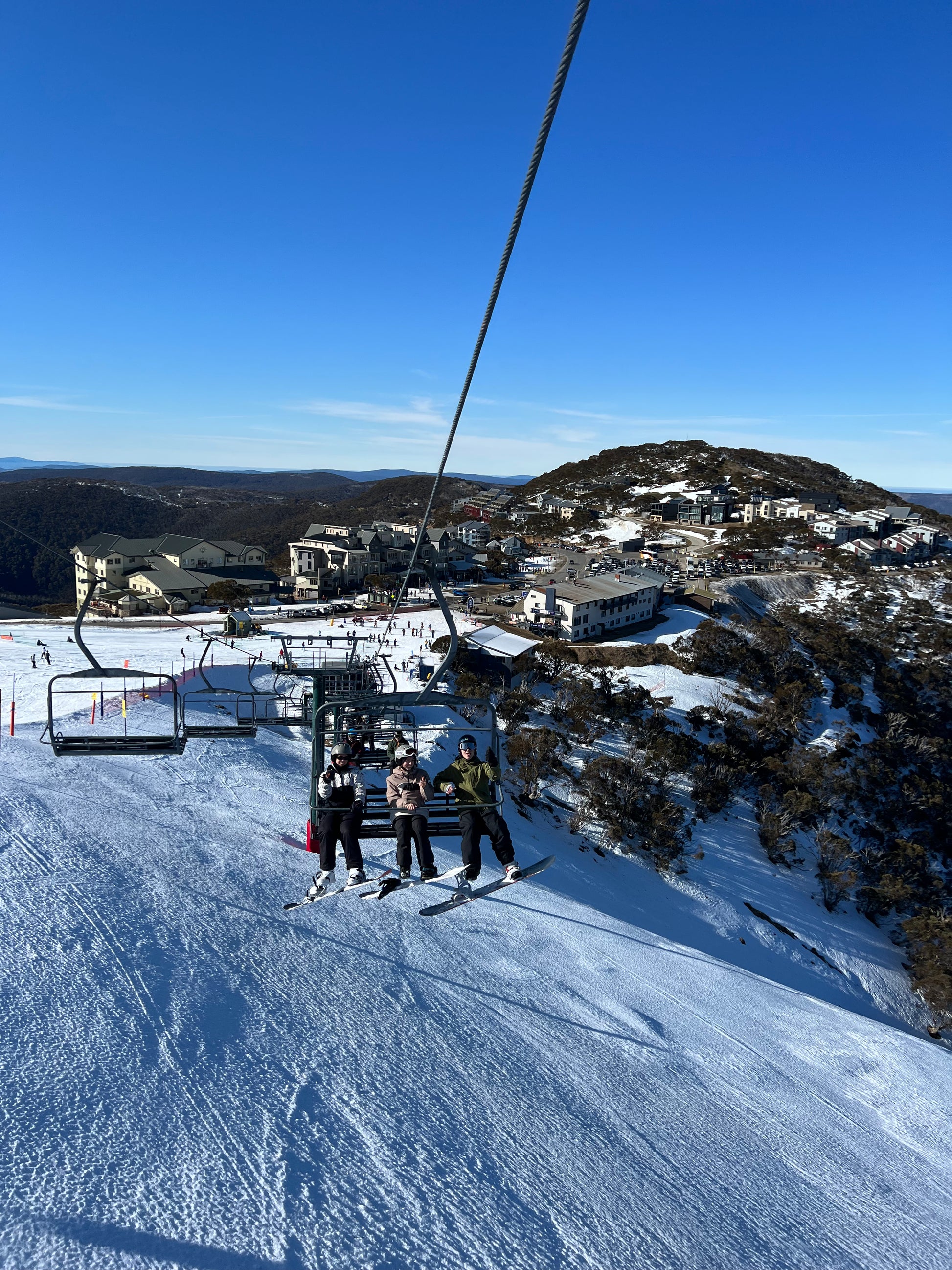 three snowboarders taking part in a Skin Ski and Surf Snow Trip on a chairlift at mount hotham